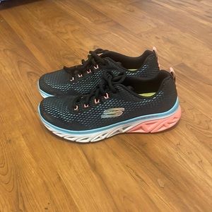 Sleeker tennis shoes. Black with blue and peach accents bare worn.